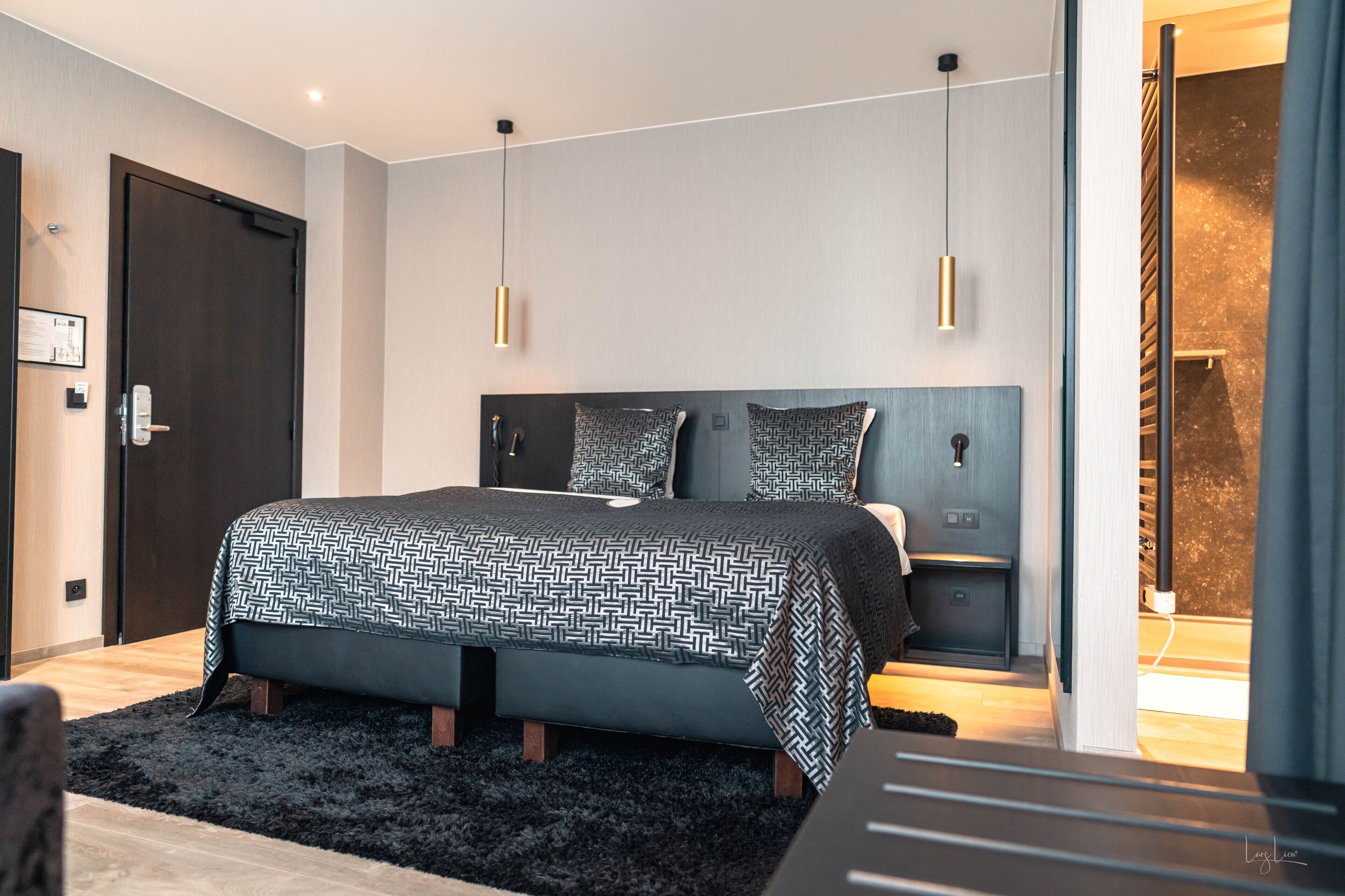 Een moderne slaapkamer met een groot bed, nachtkastjes en een donker hoofdeinde.