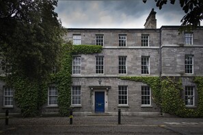 A stone building with a blue door, multiple windows, and ivy growth on the walls. - DCU Rooms Glasnevin - Hostel (Dublin)