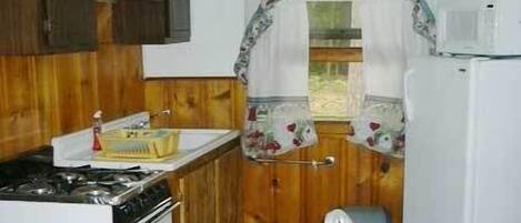 A compact kitchen with wooden cabinets, a sink, a stove, and a refrigerator.
