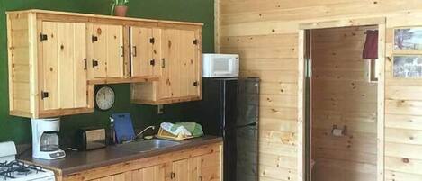 A compact kitchen with wooden cabinets, a microwave, and a stove.