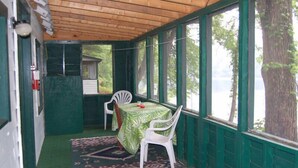 Un espace extérieur abrité, aménagé avec une table et des chaises, un tapis à motifs et offrant une vue sur un lac.
