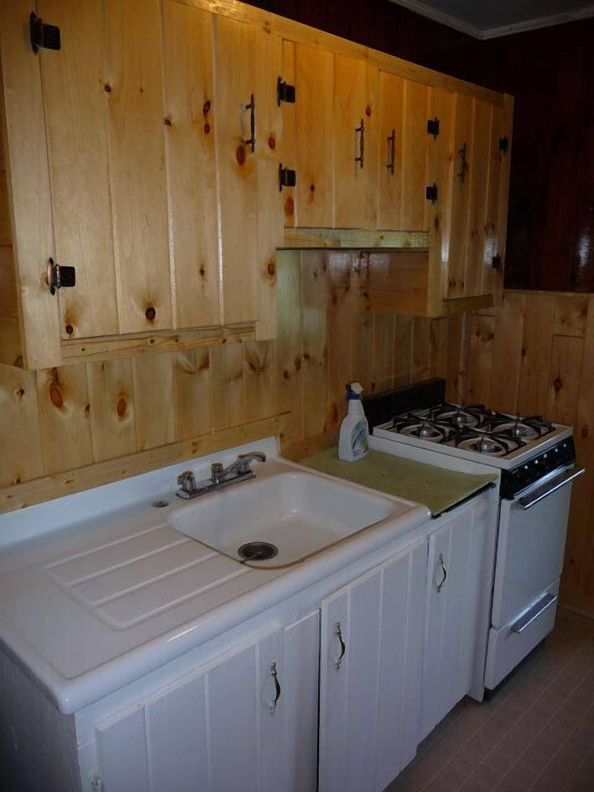 A kitchen with wooden cabinets, a white sink, and a stove.