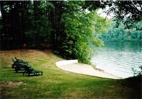 A lakeside setting with a grassy area, a curved pathway, and a bench.