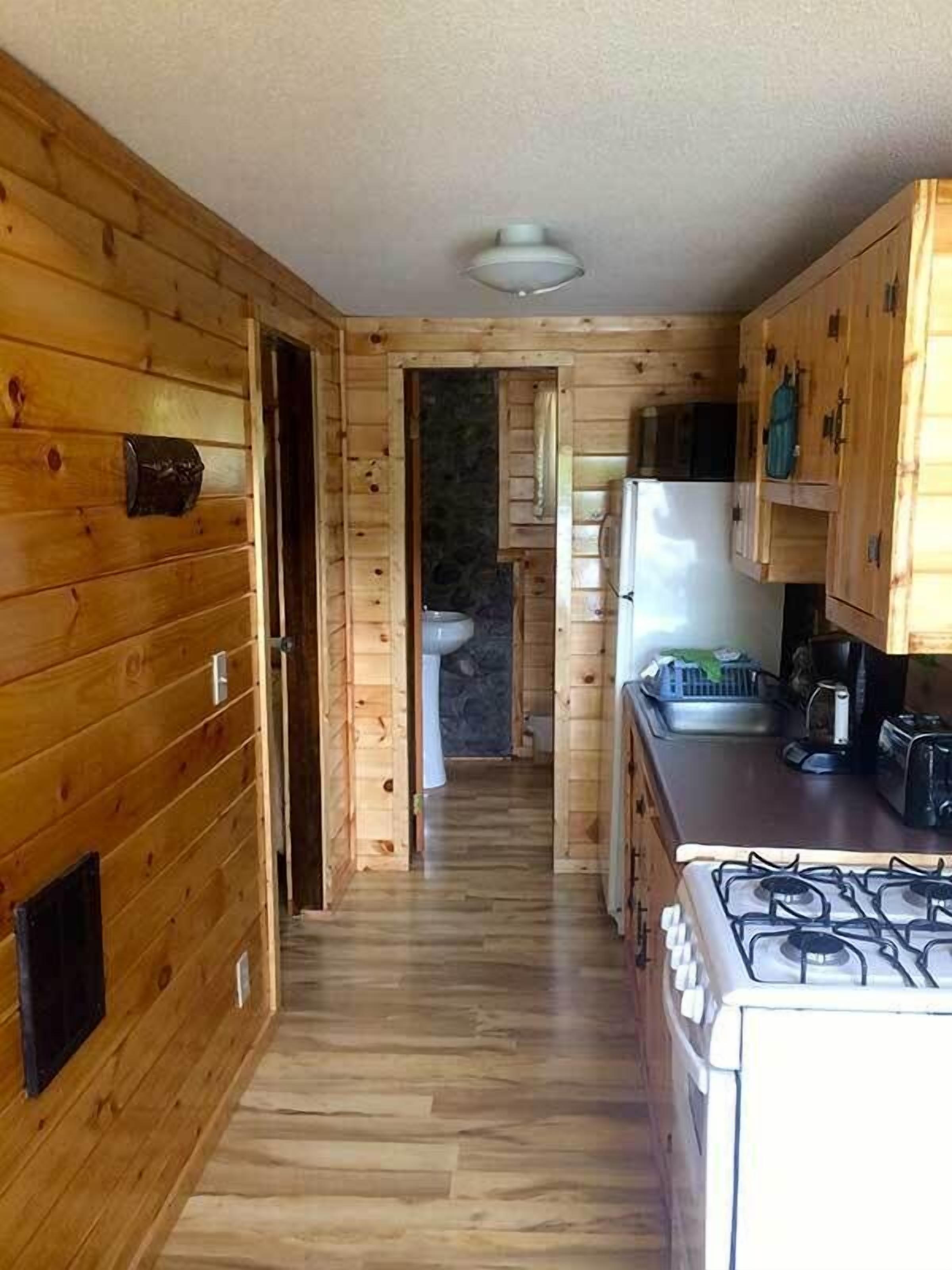 L’intérieur d’une cabane en bois comprend un espace cuisine équipé d’un poêle, d’un réfrigérateur et de placards.