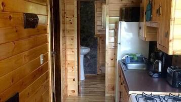 L’intérieur d’une cabane en bois comprend un espace cuisine équipé d’un poêle, d’un réfrigérateur et de placards.