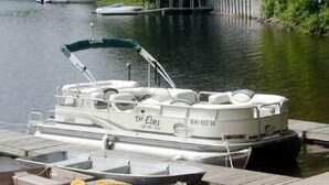 Un bateau ponton était amarré à un quai en bois, doté d’un espace de repos couvert et d’une planche de wakeboard.