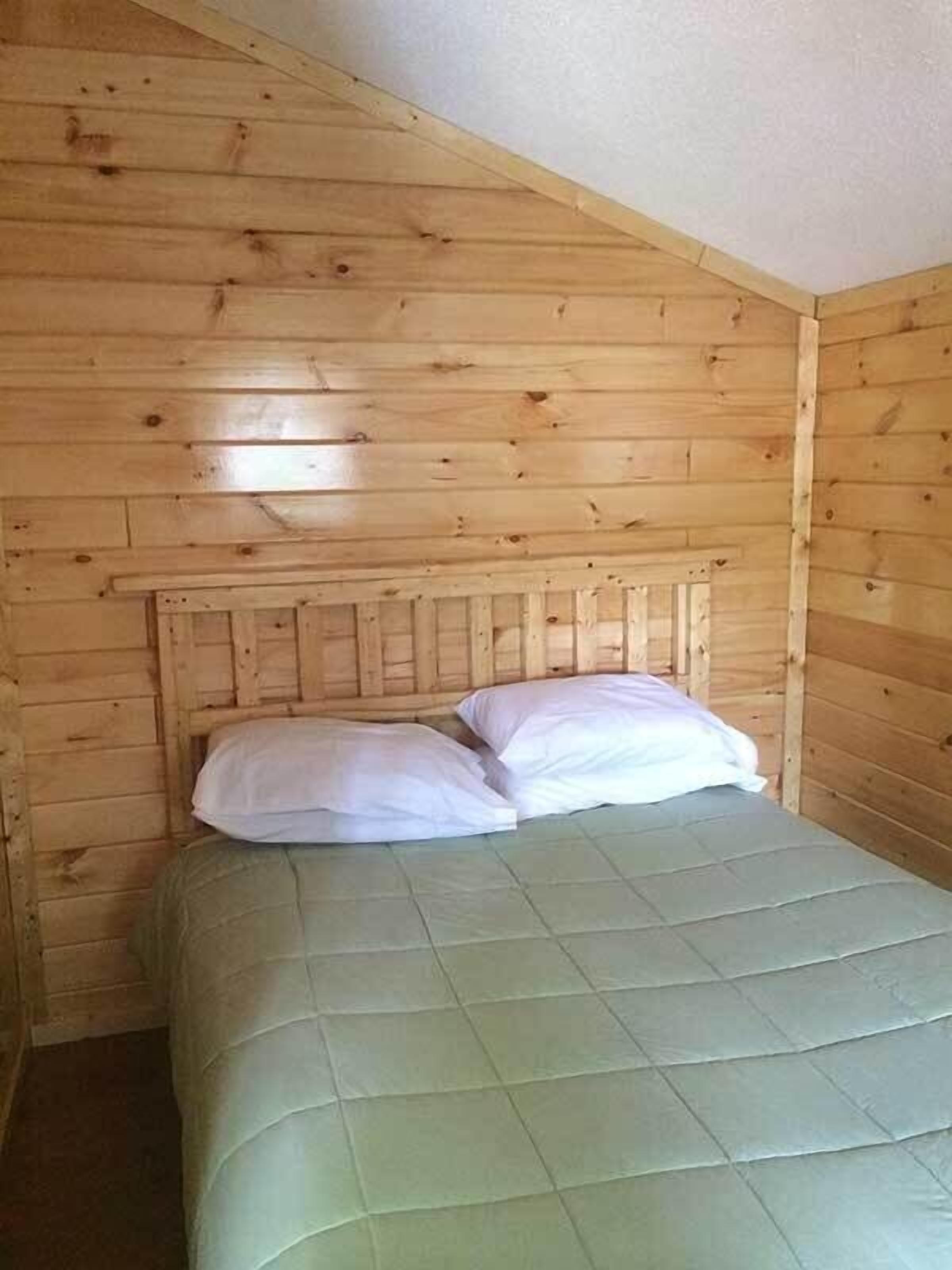 A single bed in a room with wooden paneling on the walls and ceiling.