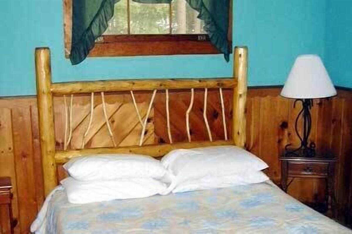 A wooden bed with white bedding in a room with blue walls and a wooden headboard.