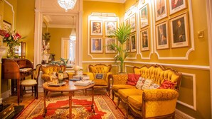 Una sala de estar tradicional con un piano, una mesa de centro y una planta grande.