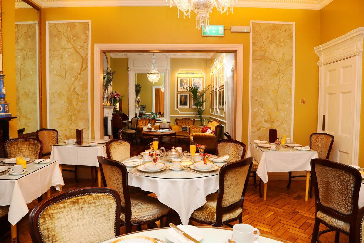 A dining area with round tables, chairs, and a chandelier.