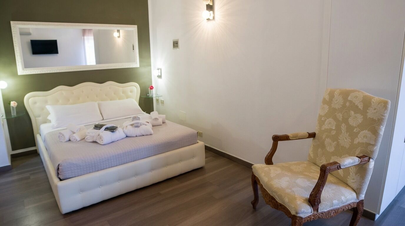 Une chambre à coucher avec un lit, une chaise, un miroir et un téléviseur fixé au mur.