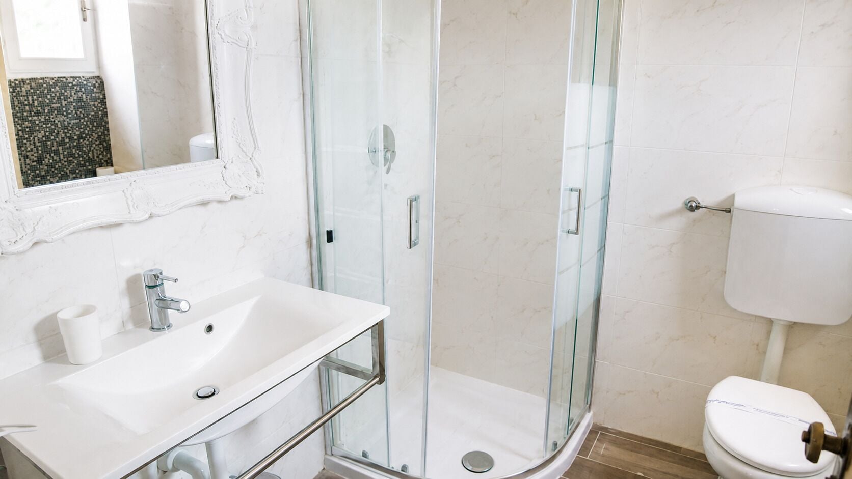 Ein Badezimmer mit Duschkabine, Waschbecken in Weiß und Toilette.