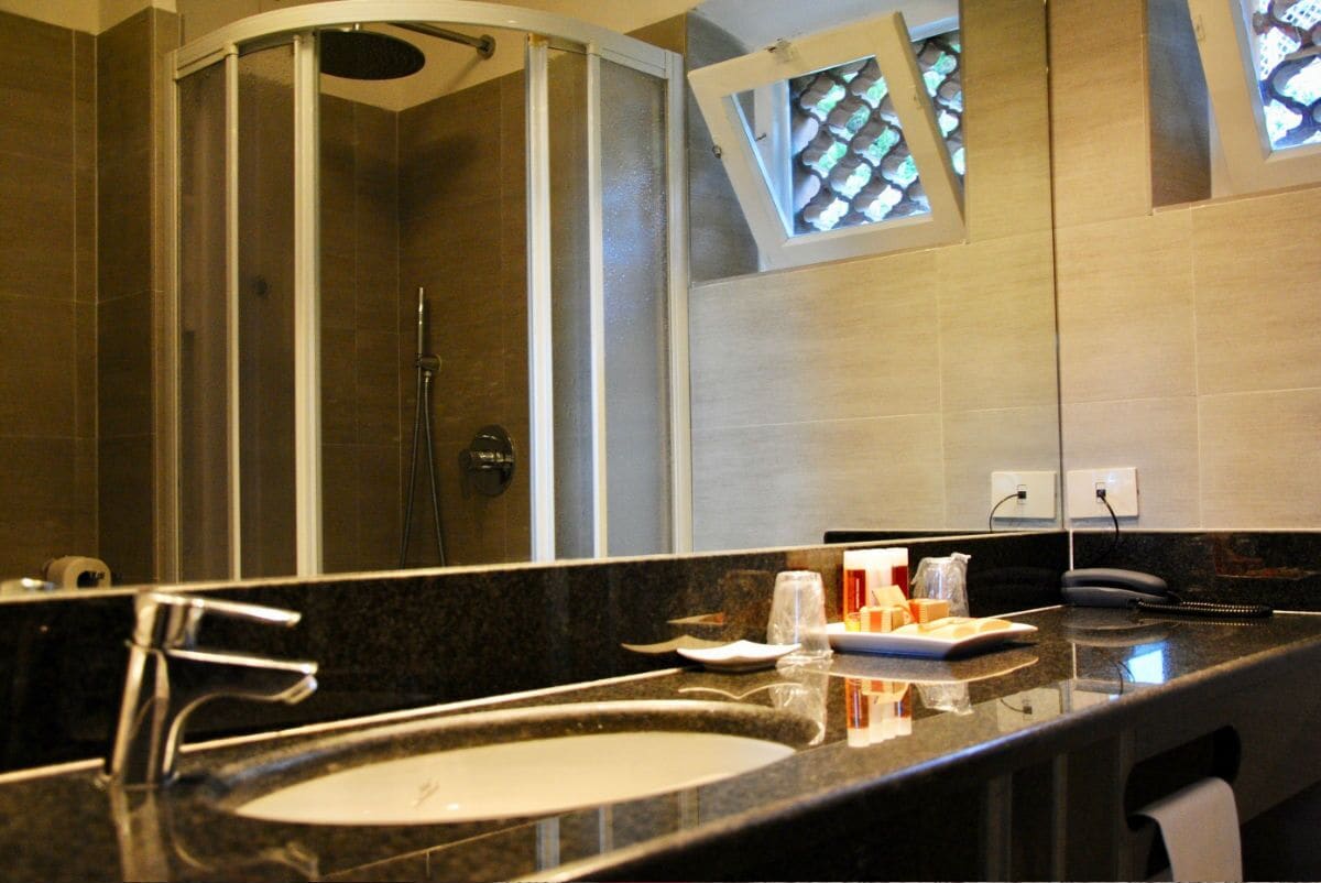 Un bagno con lavandino, specchio, doccia e una finestra con vista.