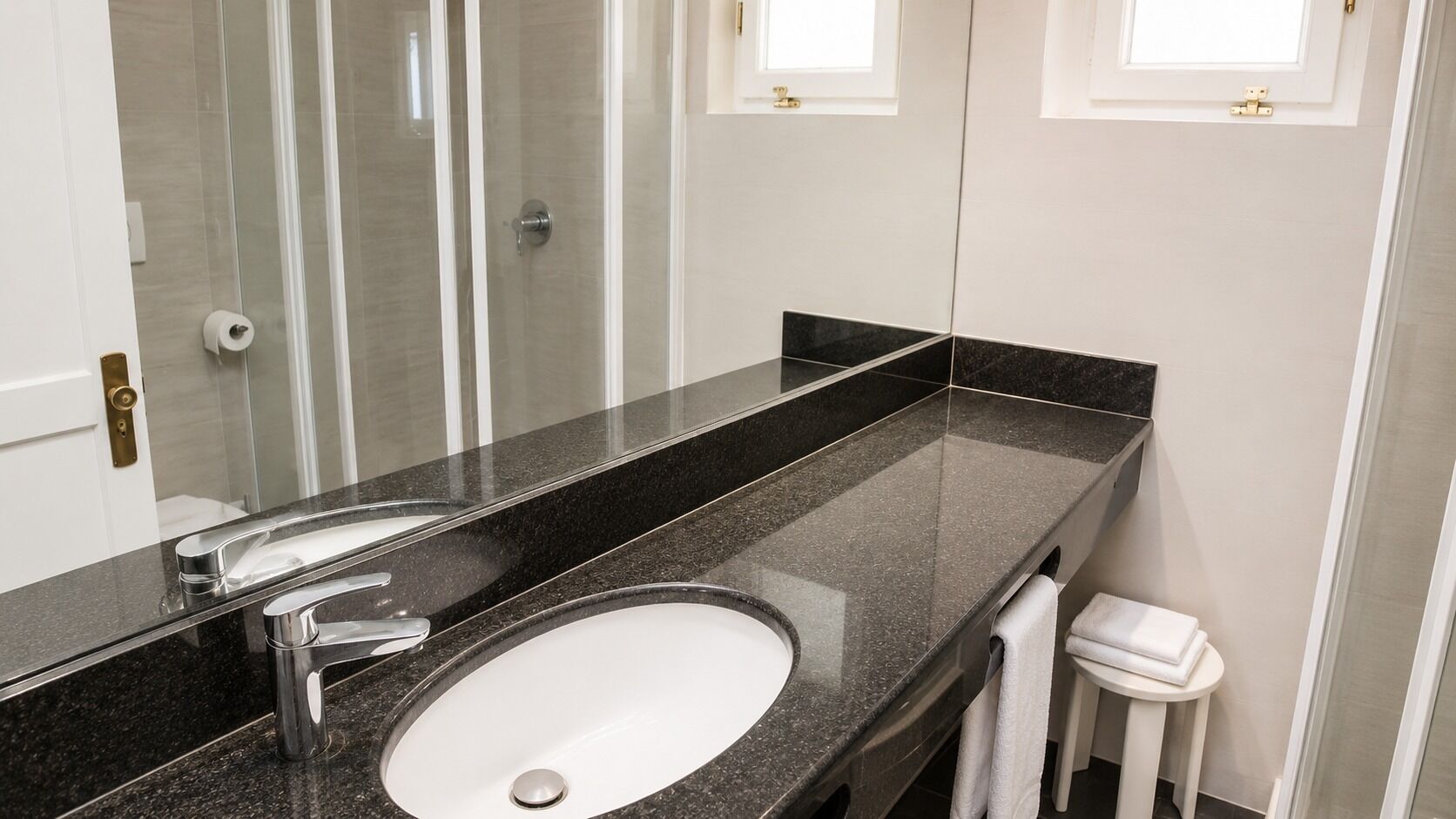 A bathroom with a large mirror, a sink, and a toilet.