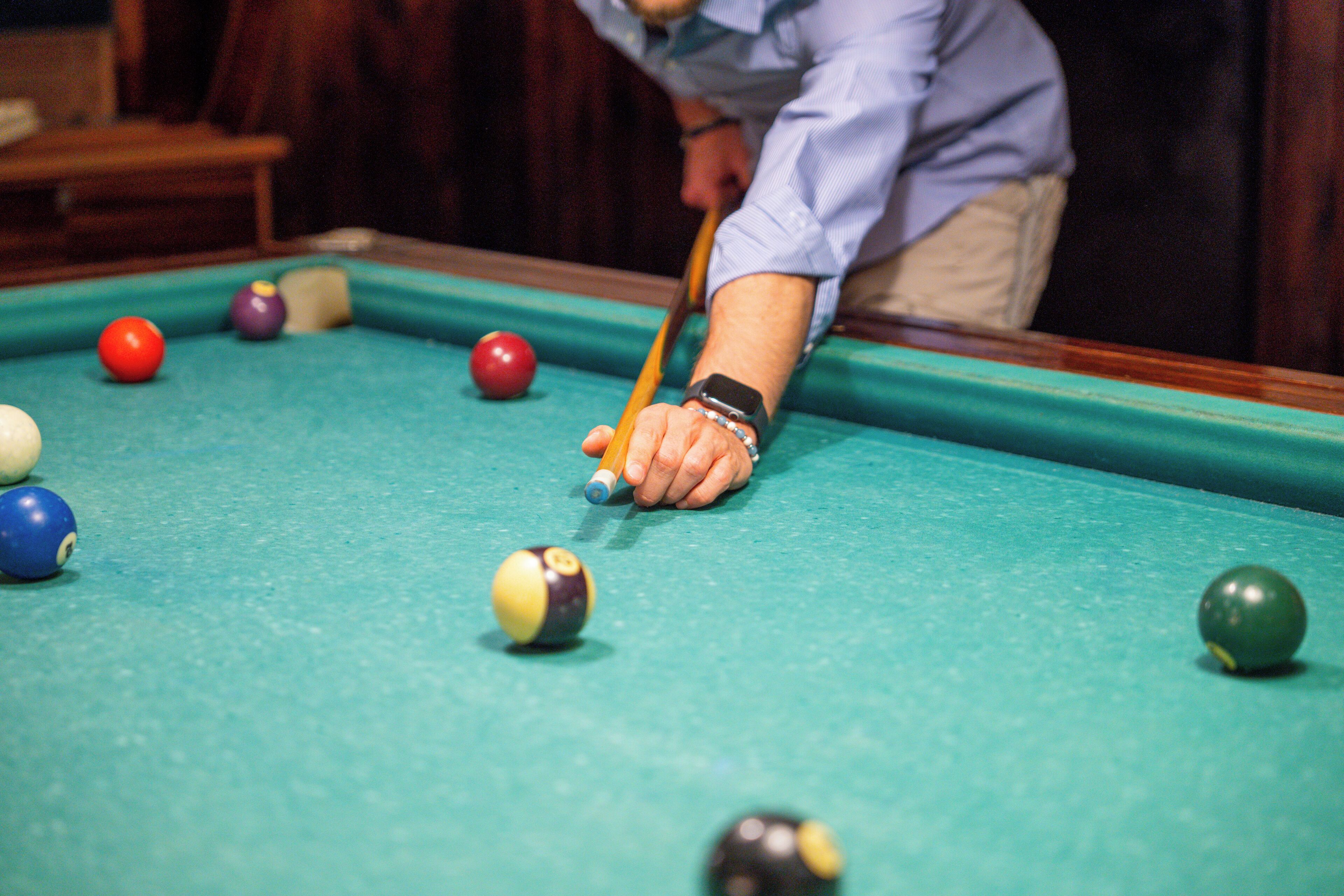 A pool table with balls and a cue stick.