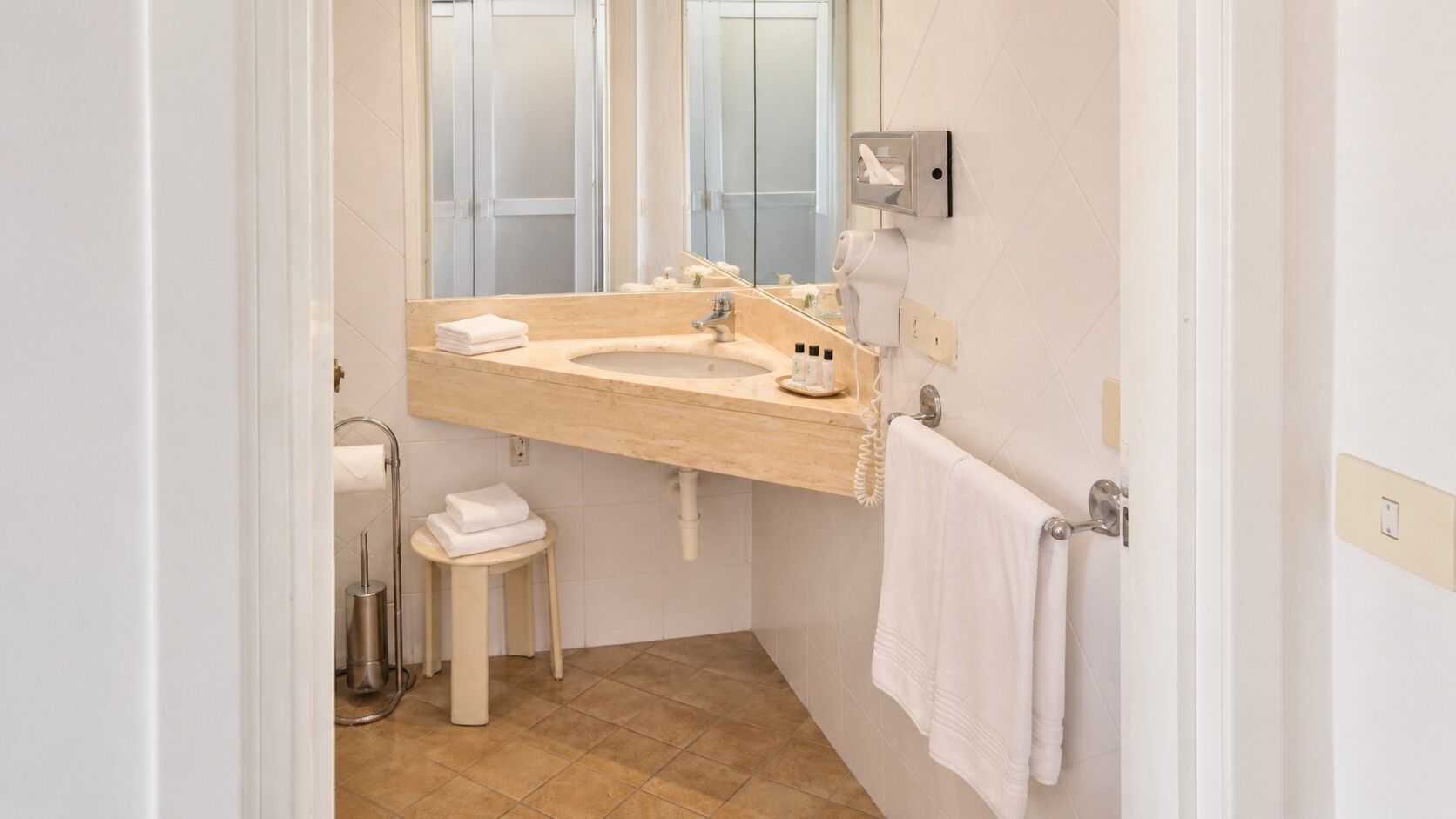 Un baño con lavabo, espejo, toallero y retrete.