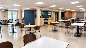Una cafetería moderna con varias mesas y sillas, una máquina de café y una barra con diversos productos.