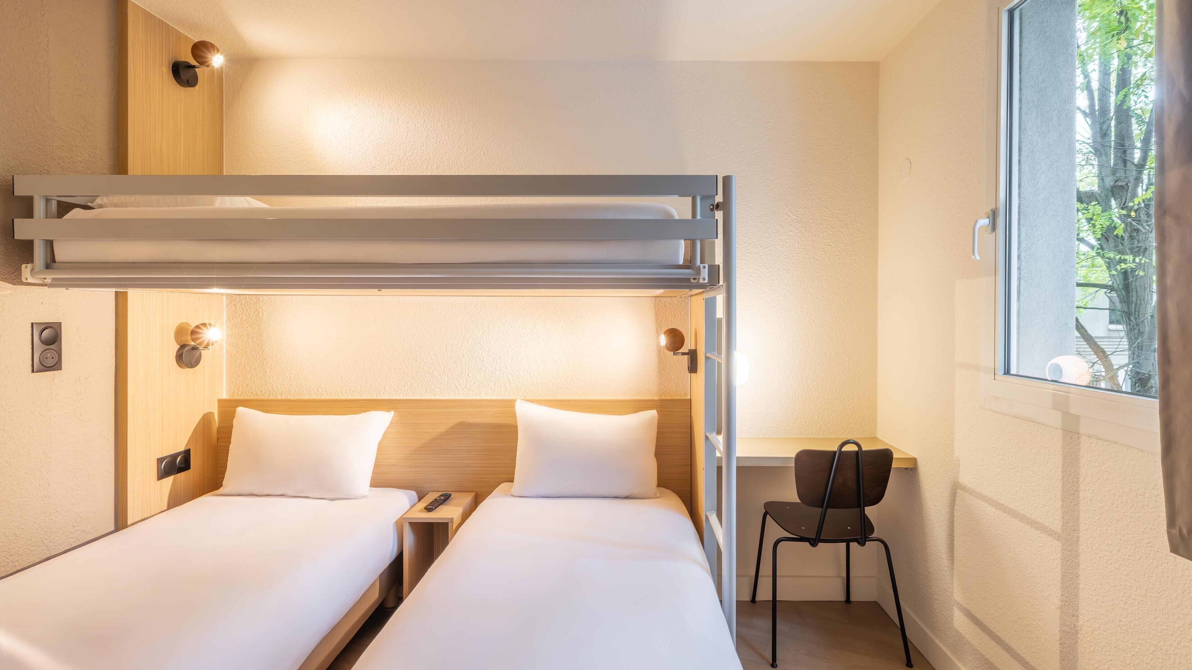 Ein Hotelzimmer mit zwei Betten, einem Schreibtisch und einem Stuhl.