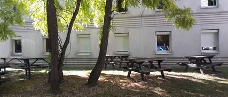Mesas de picnic al aire libre y un edificio con ventanas y contraventanas.