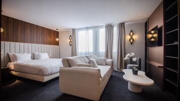 Een moderne hotelkamer met een bed, een bank, nachtkastje en een televisie.