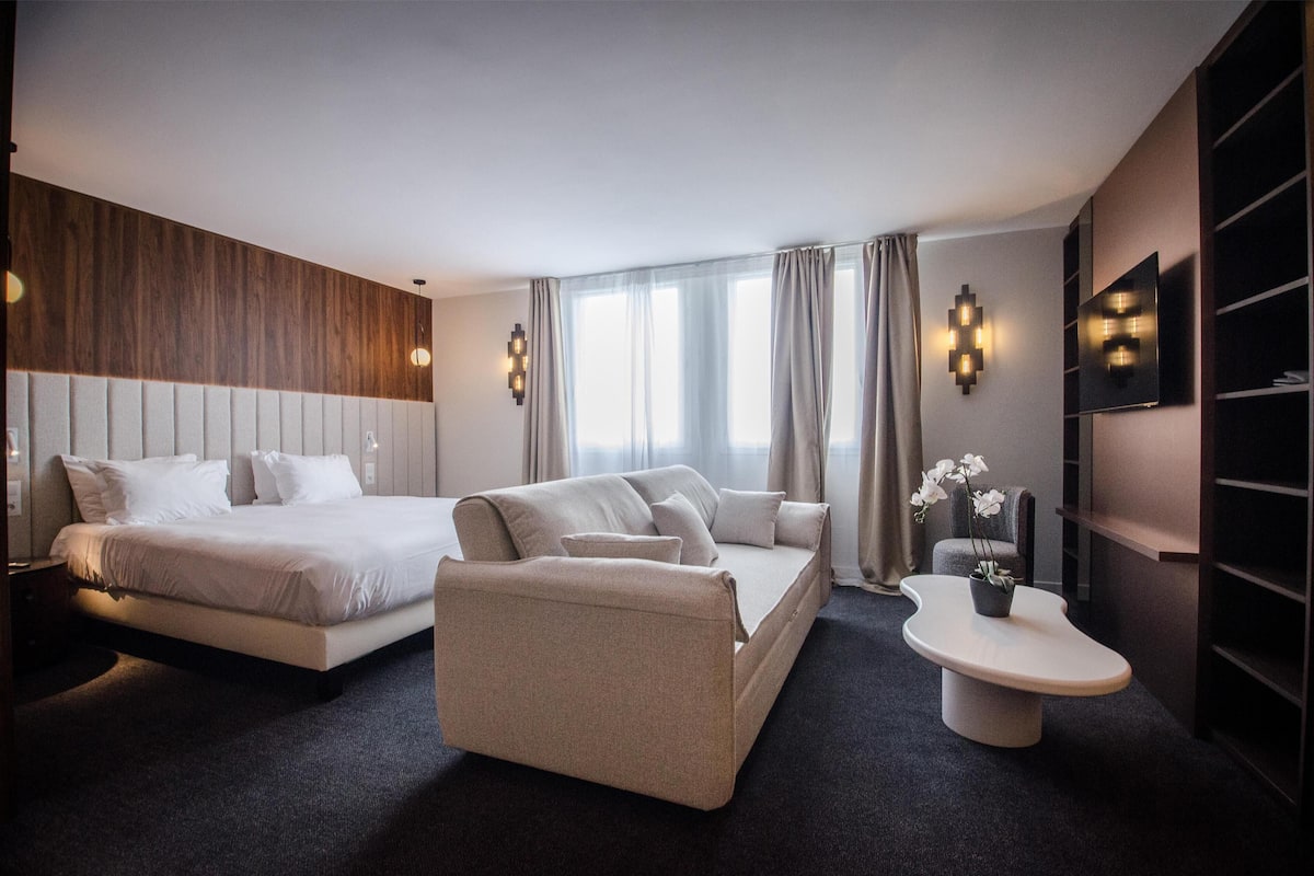 Une chambre d’hôtel moderne équipée d’un lit, d’un canapé, d’une table de chevet et d’un téléviseur.
