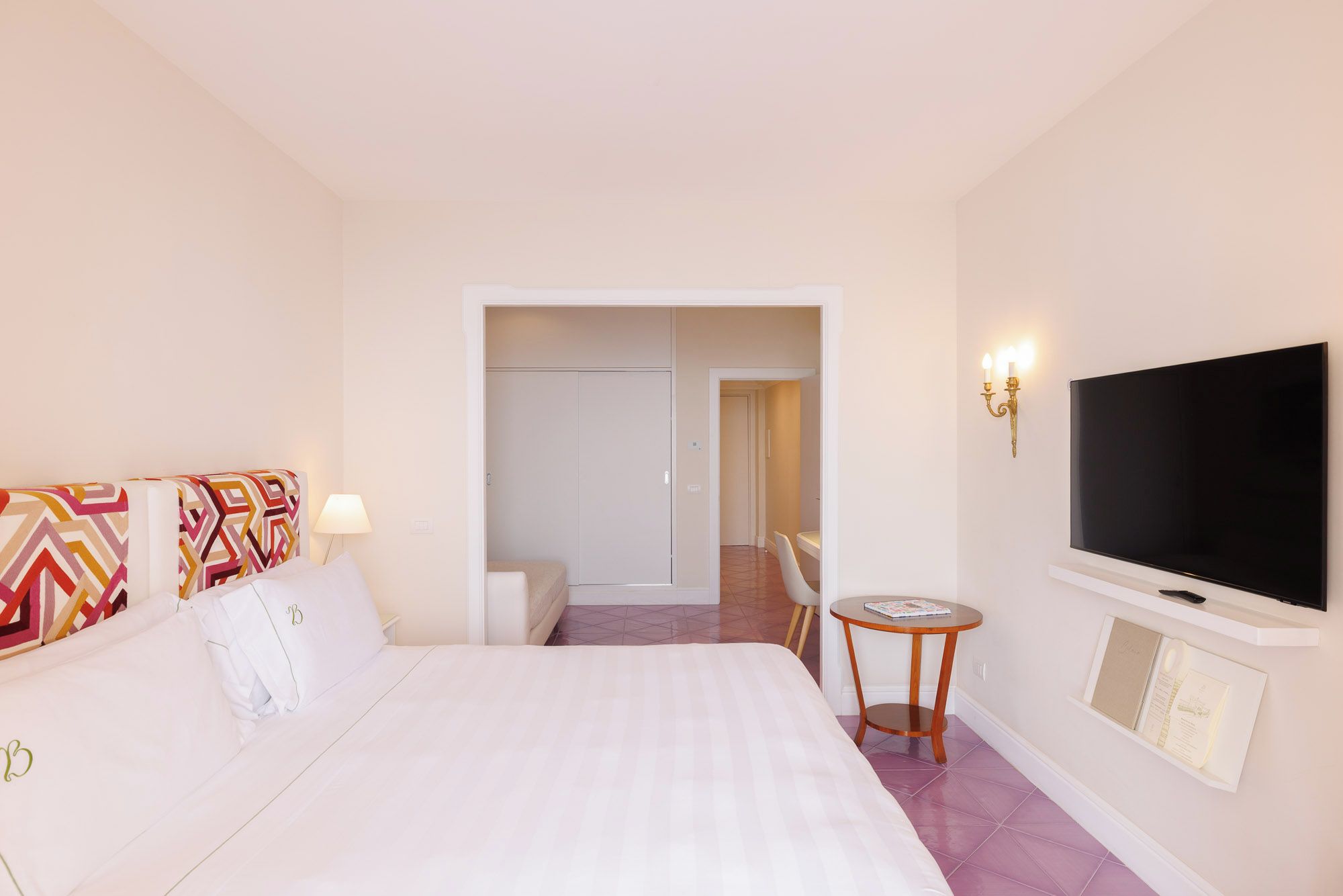 A hotel room with a bed, a TV, a small table, and a chair.