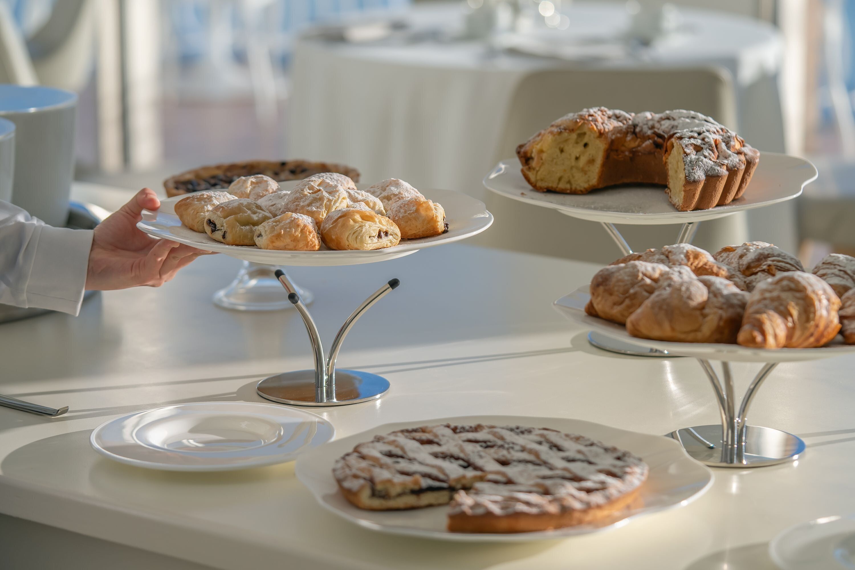 A buffet table with various pastries and desserts displayed on white plates and stands.