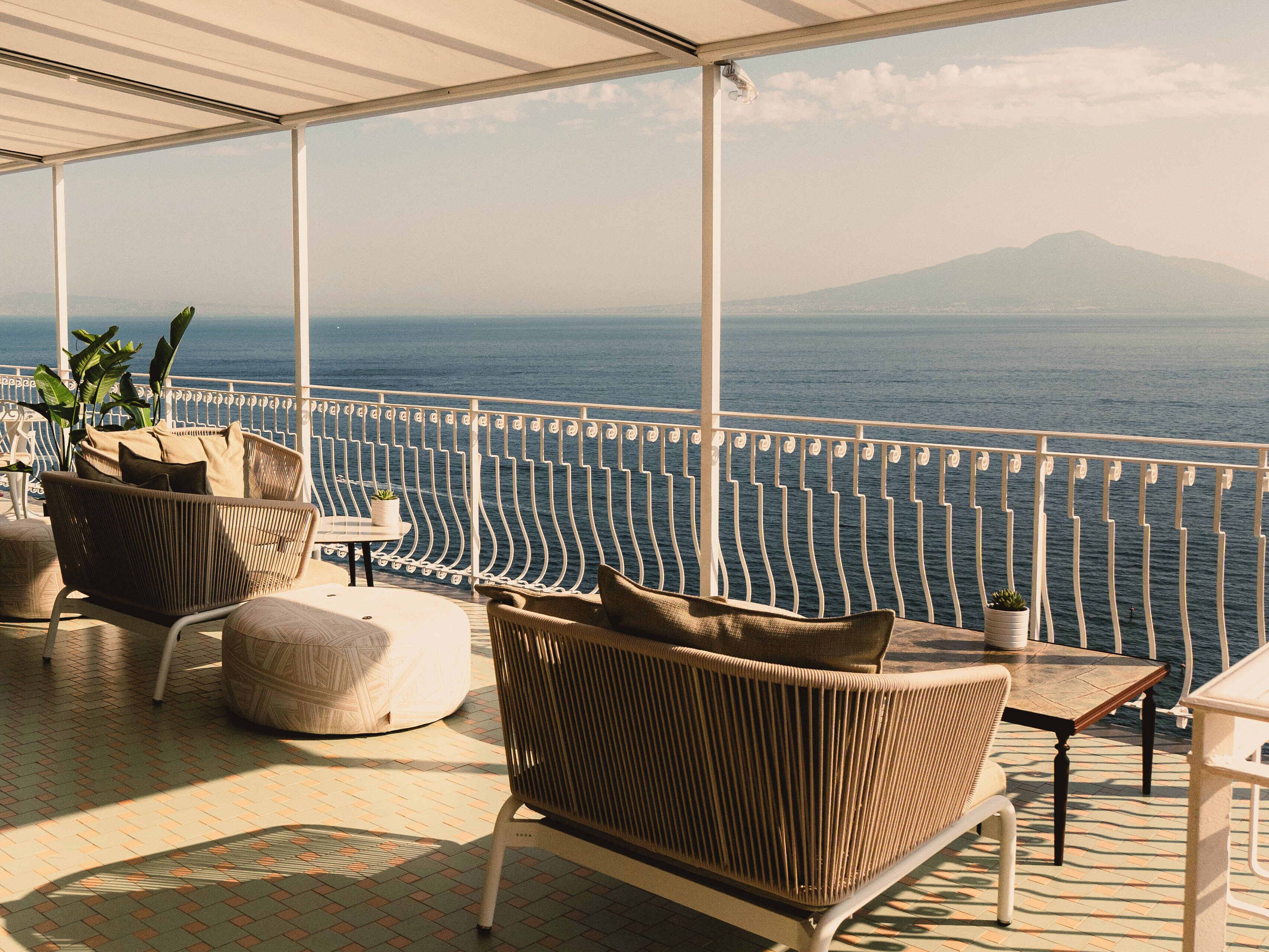 Ein überdachter Sitzbereich im Freien mit Korbmöbeln und Blick auf das Meer.