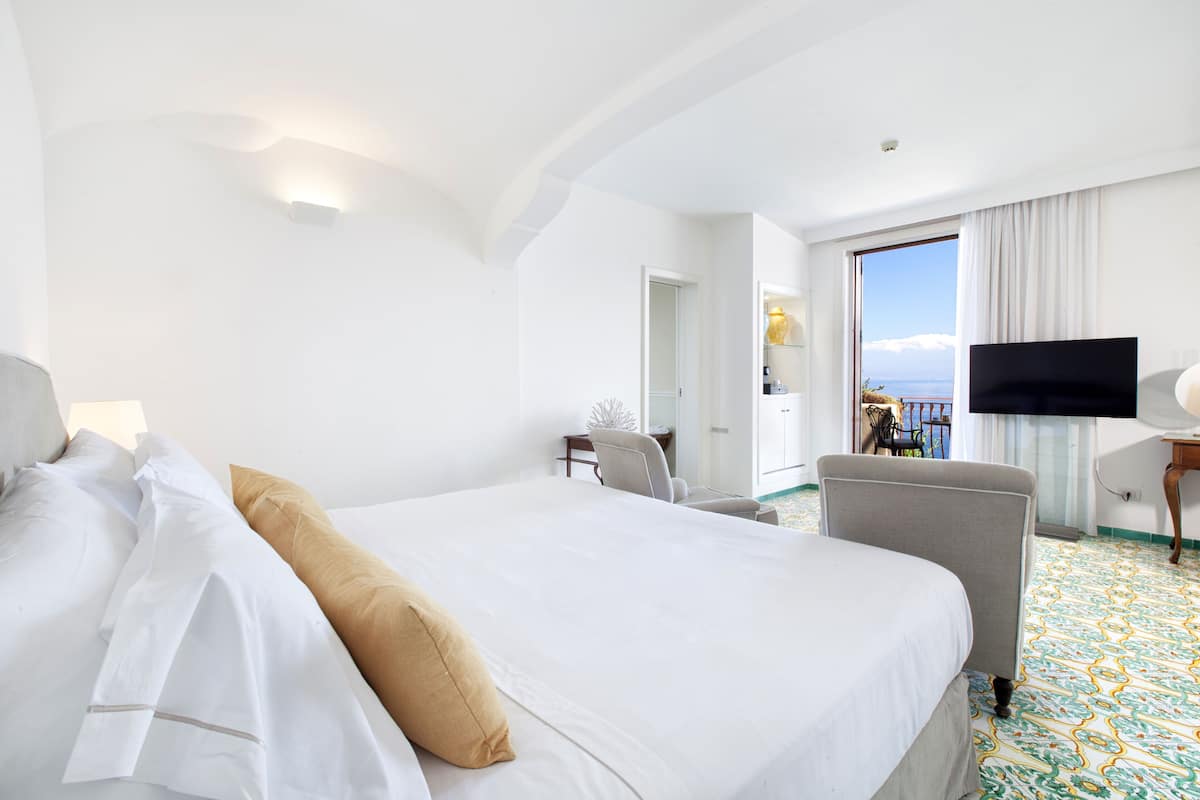 Una camera d'albergo con un letto grande, una televisione, una scrivania e vista mare.