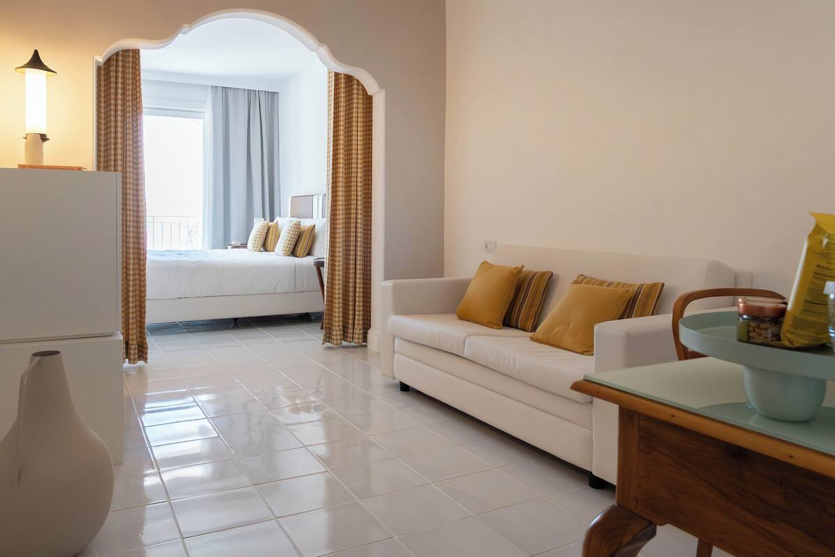 Una camera d'albergo con un letto, un divano, un tavolo da pranzo e una lampada.