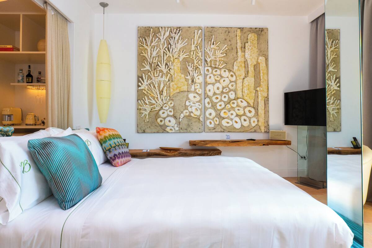 Una camera d'hotel moderna con un letto grande, una TV a schermo piatto e un'opera d'arte a parete.
