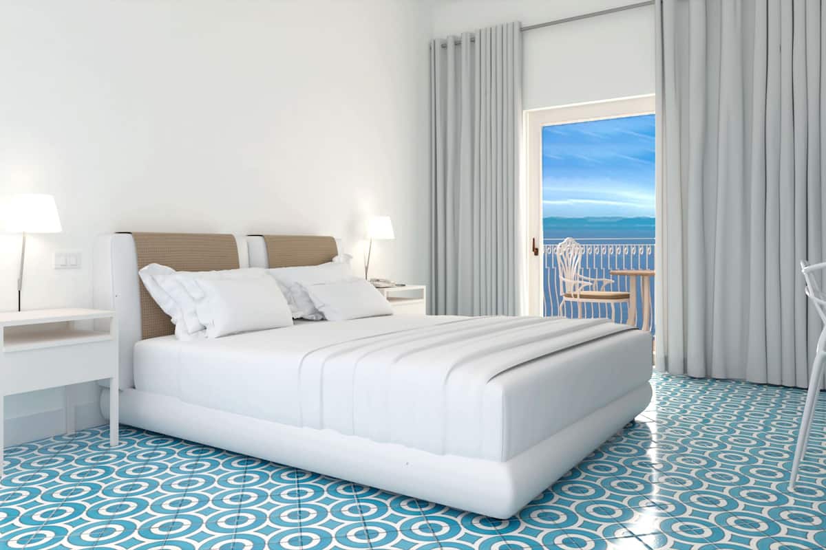 Una camera d'albergo moderna con un letto grande, un comodino, una sedia e un balcone con vista.