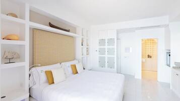 Een moderne slaapkamer met een groot bed, inbouwkasten en een badkamer met een glazen deur.