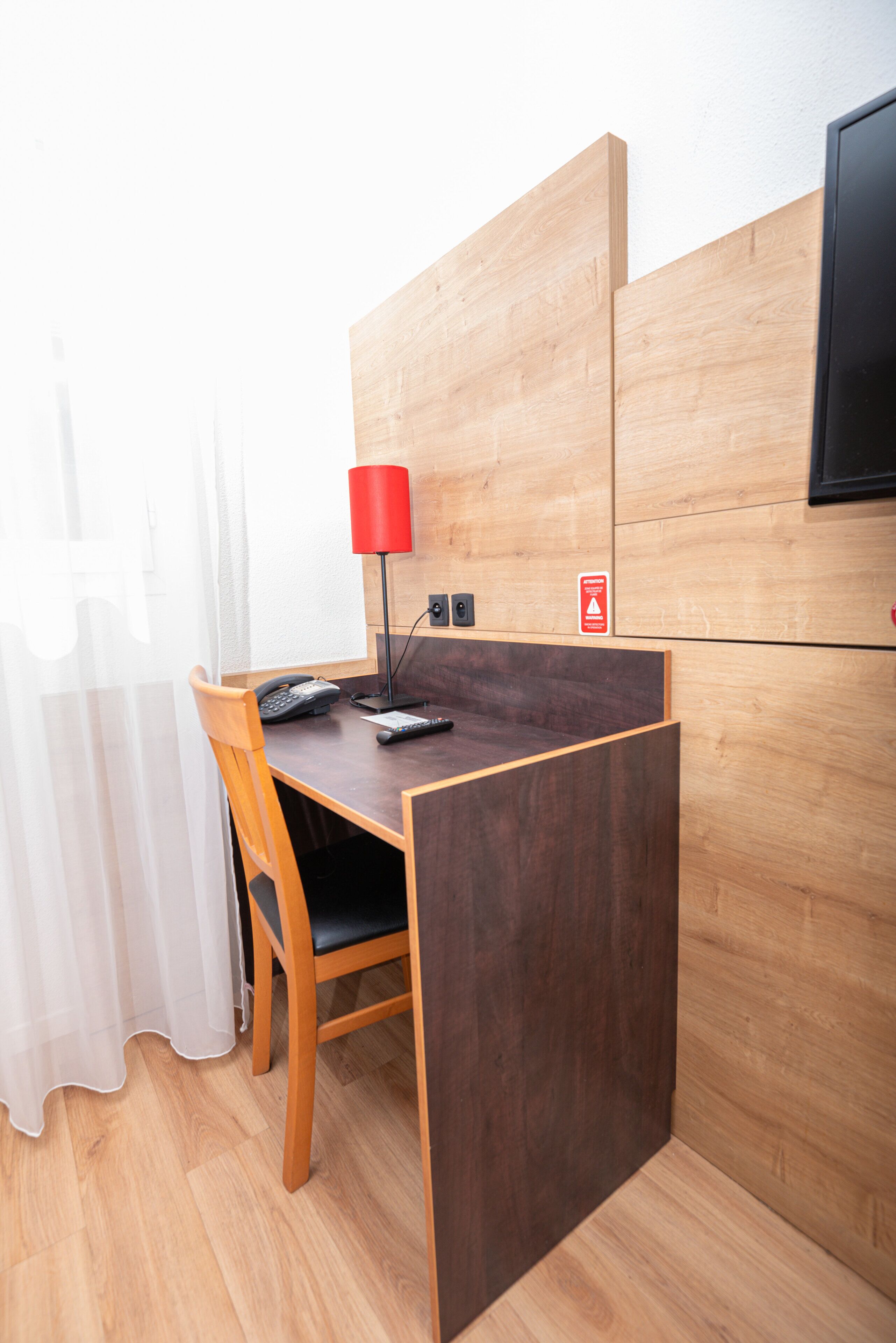 Un petit bureau privé, équipé d’un bureau, d’une chaise et d’une lampe rouge.