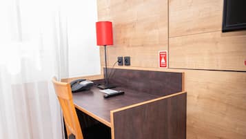 Un petit bureau privé, équipé d’un bureau, d’une chaise et d’une lampe rouge.