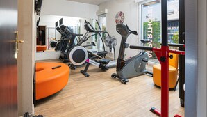 A gym with various exercise equipment, including treadmills, stationary bikes, and a rowing machine. - Apparthôtel Privilodges Lyon (Lyon)
