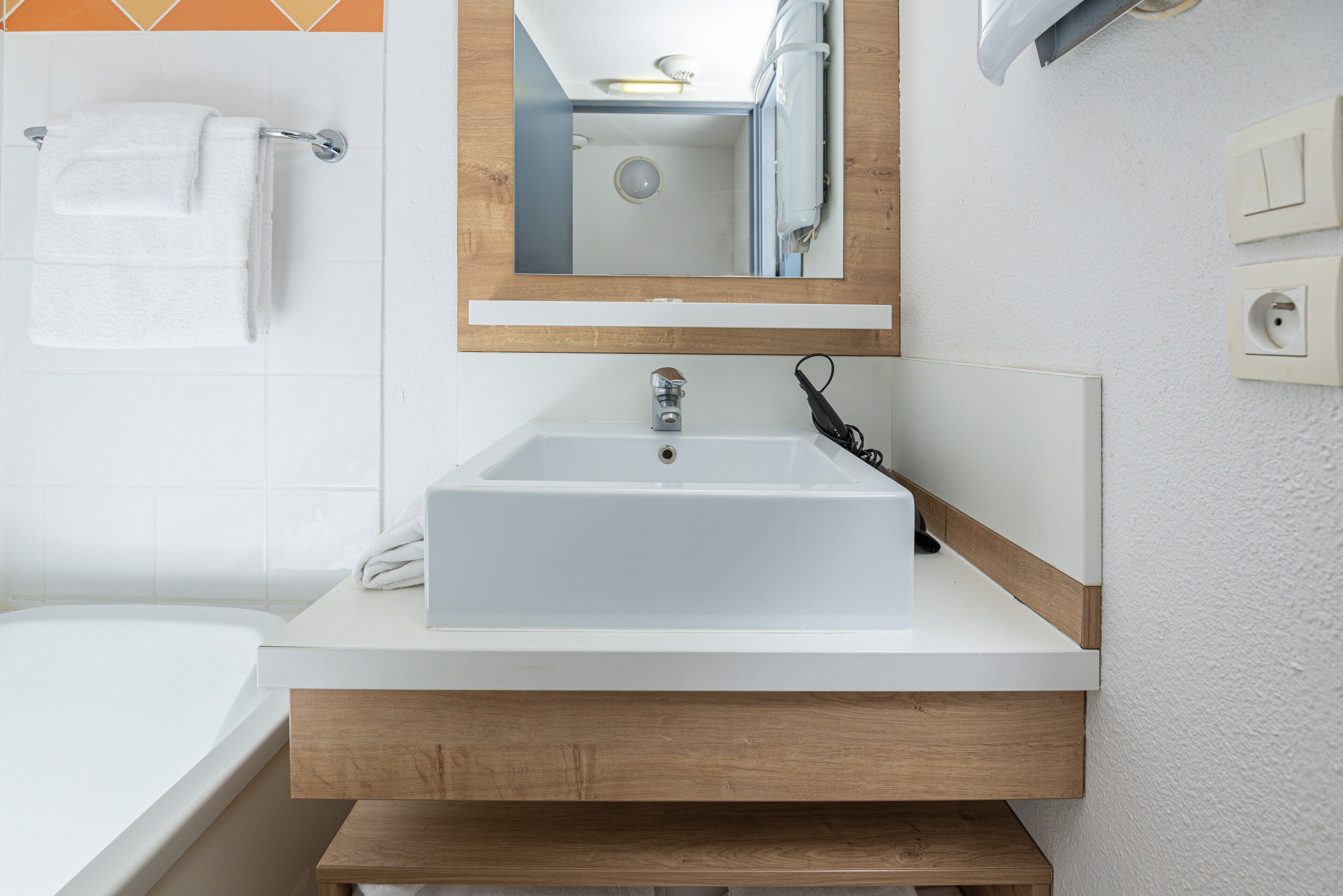 Une salle de bain avec un lavabo blanc, un miroir et un porte-serviettes.