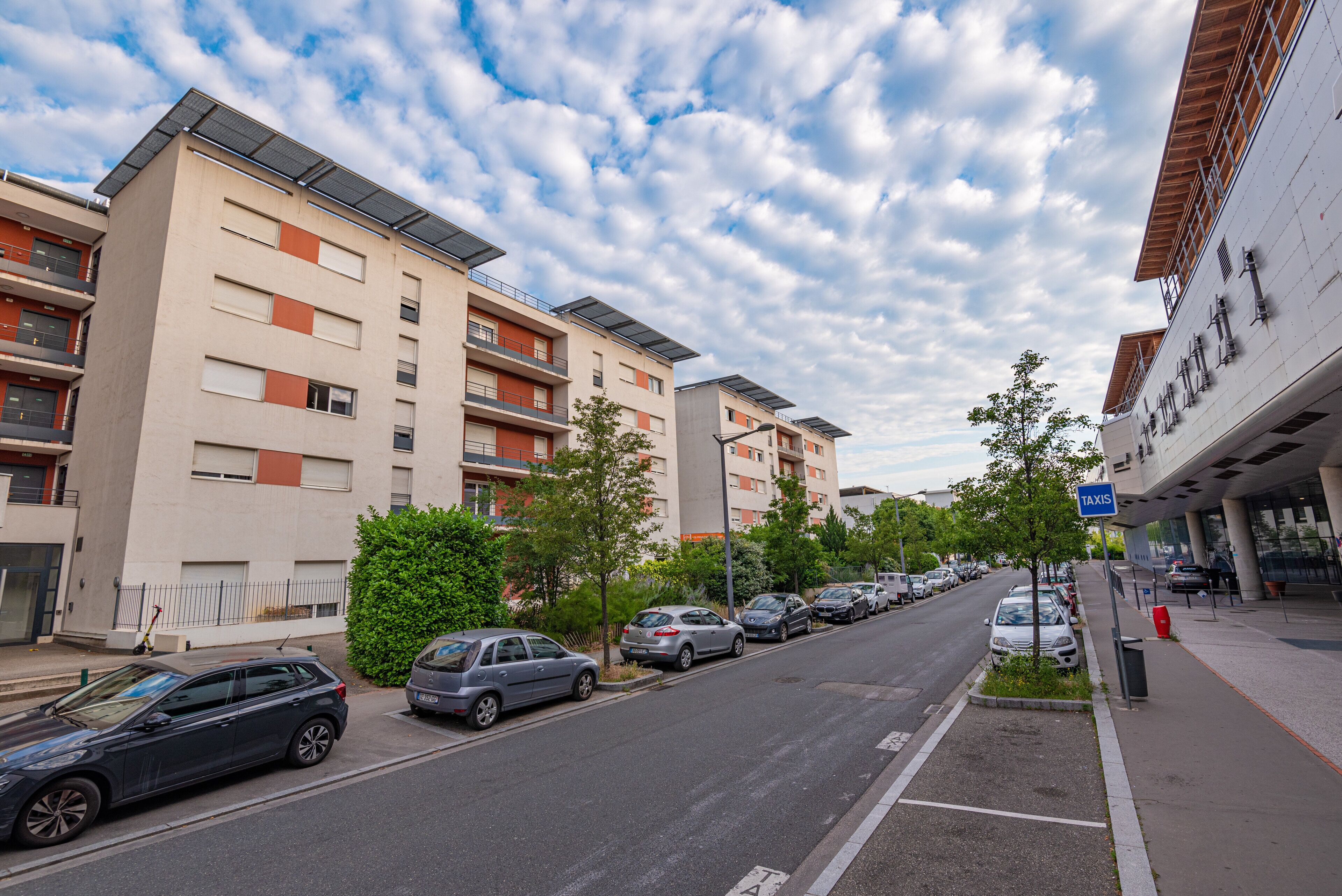 A multi-story residential building with balconies and solar panels.