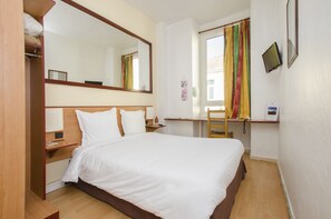 A hotel room with a bed, a desk, a chair, a mirror, and a window with curtains. - Hotel Bosquet Pau Centre (Pau)