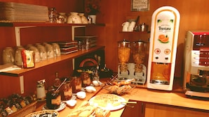 Een ontbijtbuffet met diverse etenswaren, een koffieapparaat en een fruitsapdispenser.