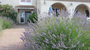A building with a reception area, arched windows, and a pathway leading to it. - Brit Hotel Bosquet (Carcassonne)