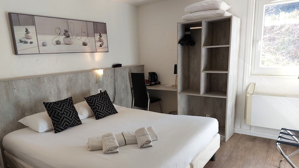A hotel room with a large bed, a desk, a chair, and a wardrobe. - Brit Hotel Bosquet (Carcassonne)