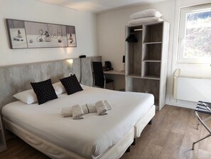 A hotel room with a large bed, a desk, a chair, and a wardrobe. - Brit Hotel Bosquet (Carcassonne)