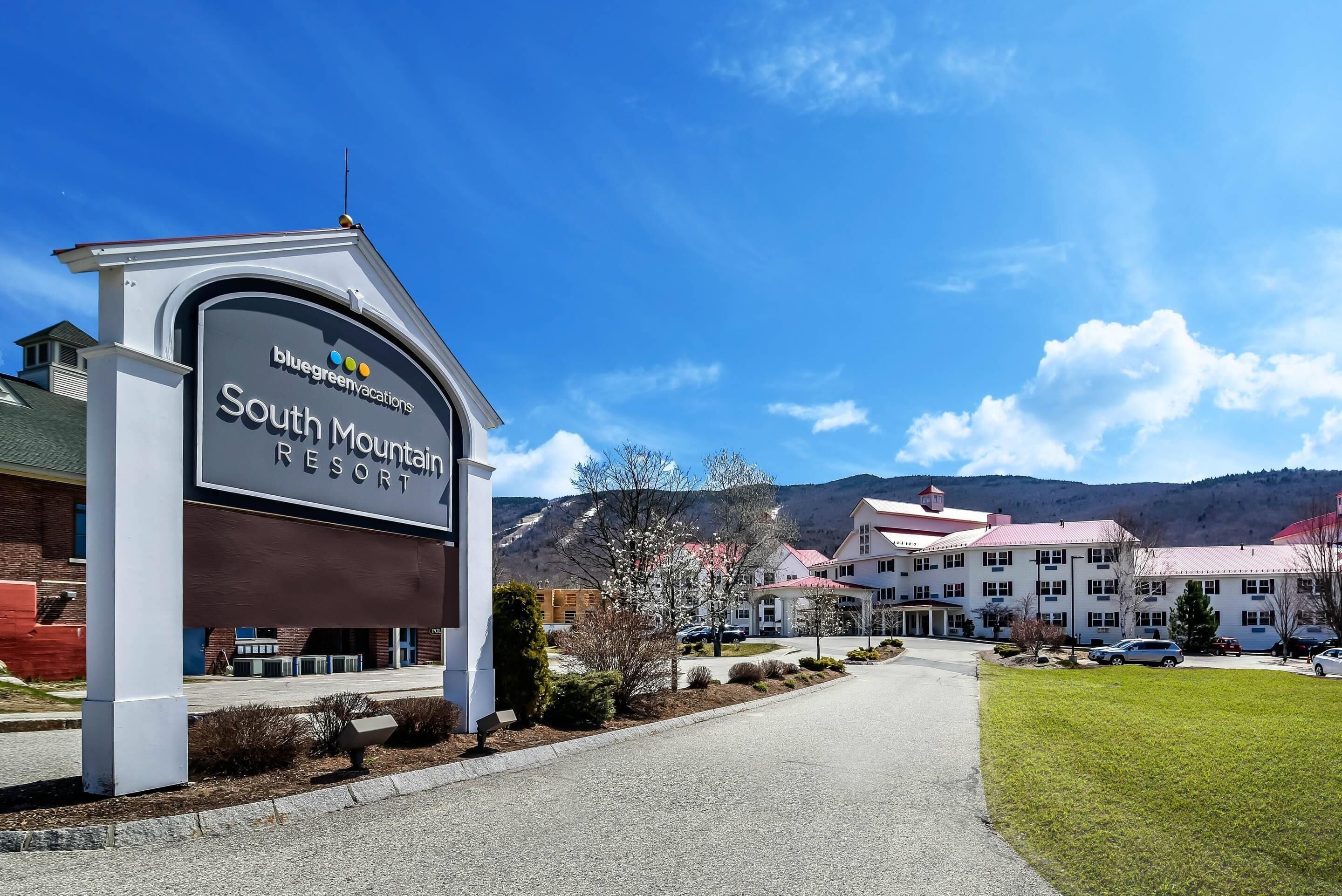 A sign for BlueGreen Vacations South Mountain Resort with a clear sky and mountains in the background.
