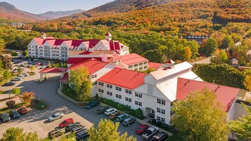 Un hotel con varias construcciones, estacionamiento y montañas al fondo.