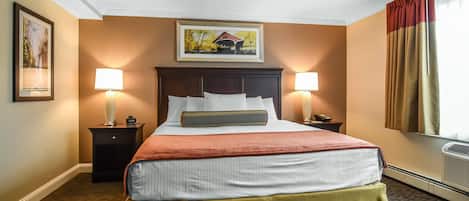 A hotel room with a large bed, two bedside tables with lamps, a ceiling fan, and a painting on the wall.