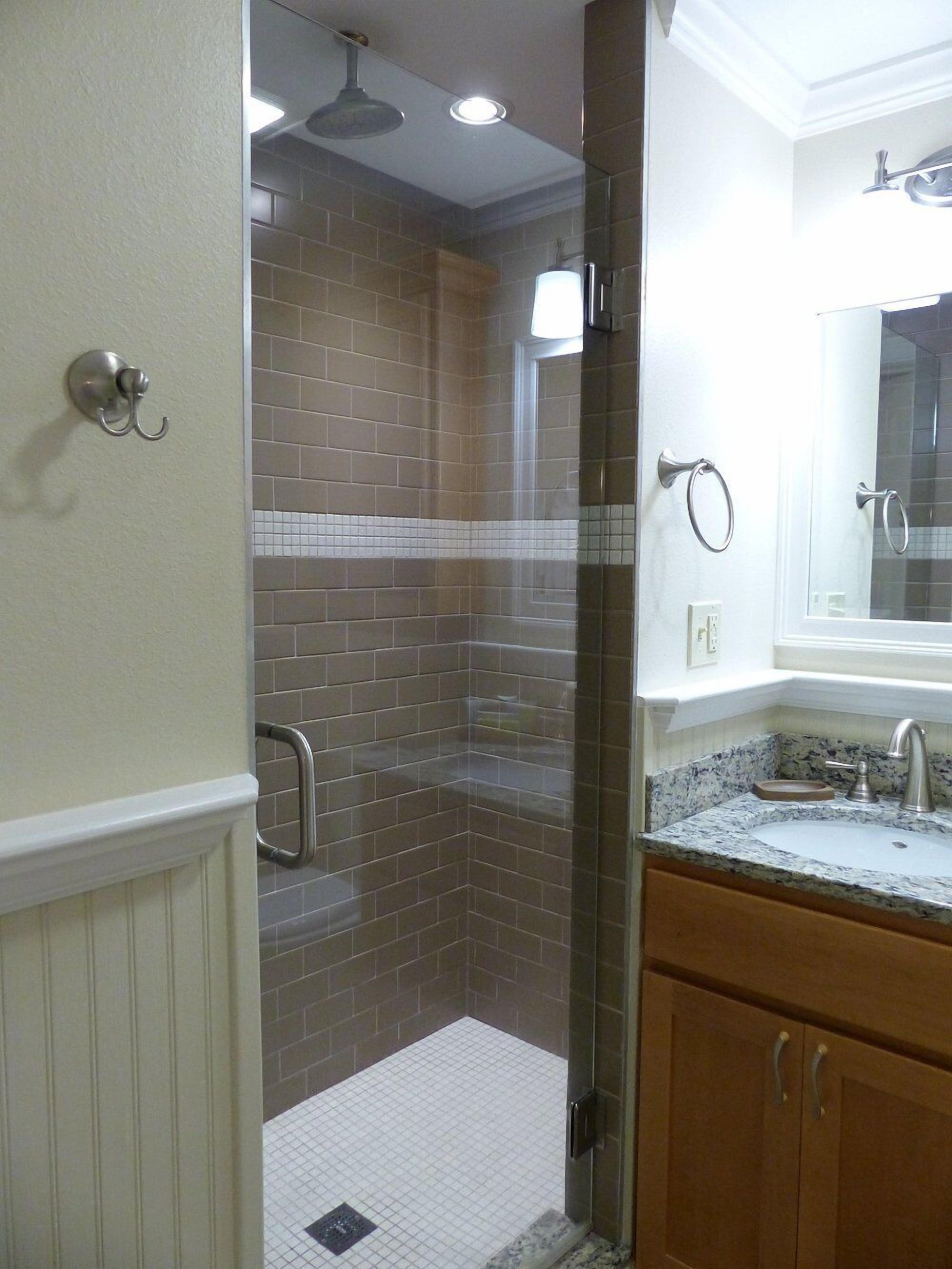 Une salle de bain avec une douche, un lavabo et un miroir.