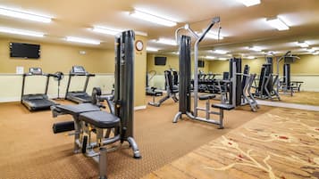 A gym with treadmills, weight machines, and a carpeted floor.