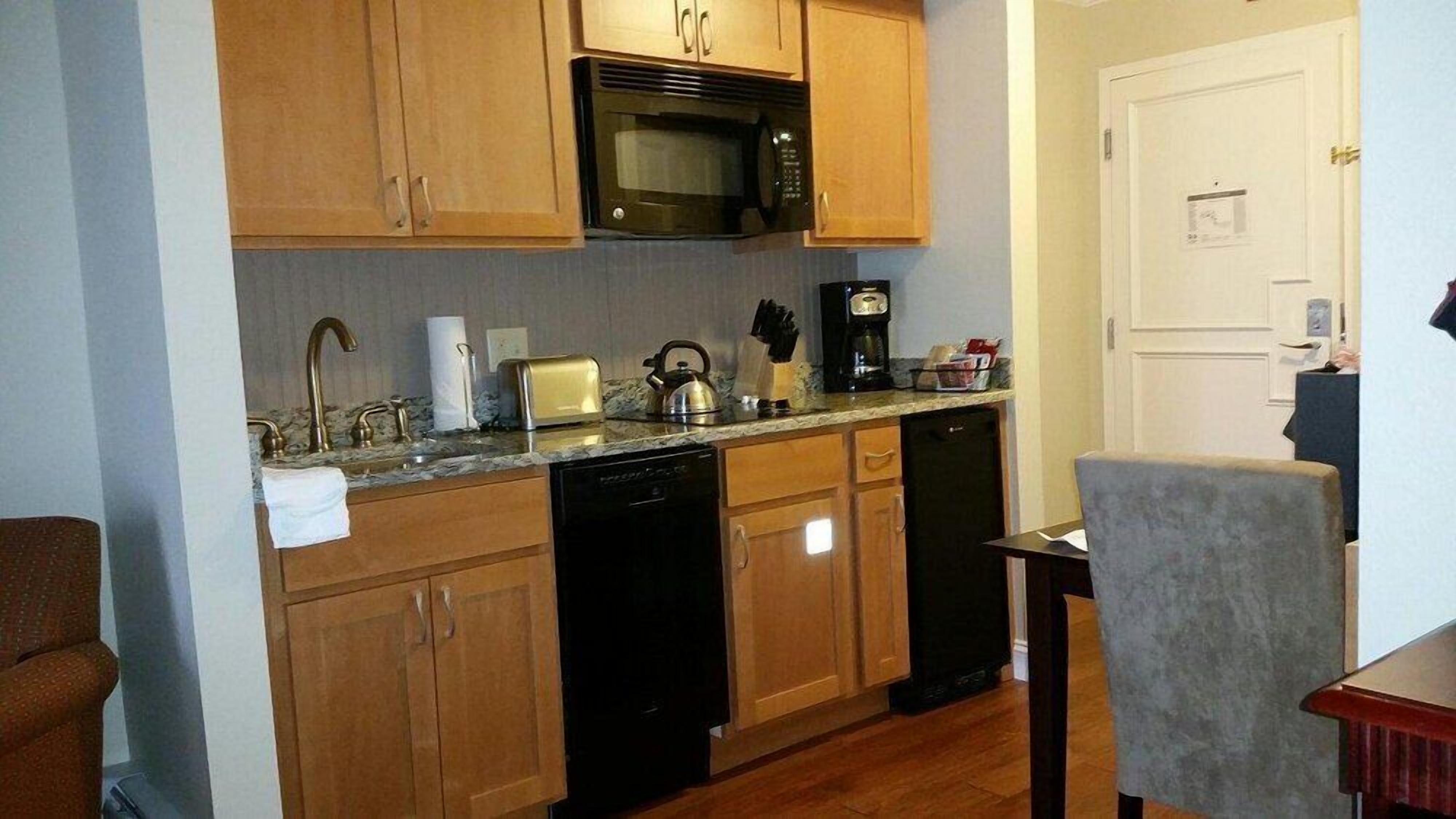 A compact kitchen with wooden cabinets, a microwave, a toaster, and a coffee maker.