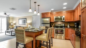 A modern kitchen with wooden cabinets, stainless steel appliances, and a central island with bar stools. - Bluegreen Vacations South Mountain, an Ascend Collection Resort (Lincoln)